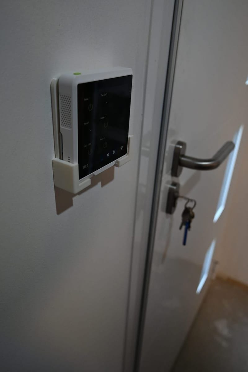 L'écran tactile YnerPlay installé au mur sur son support, à côté d'une porte